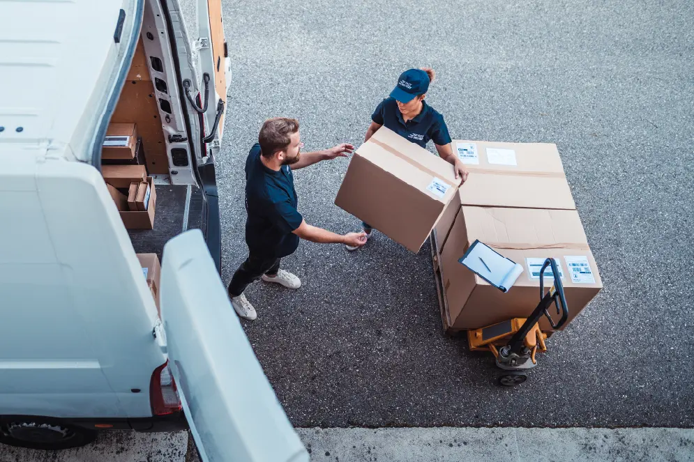 Two people outside of a pickup van moving boxes.